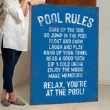 a woman standing next to a pool rules sign