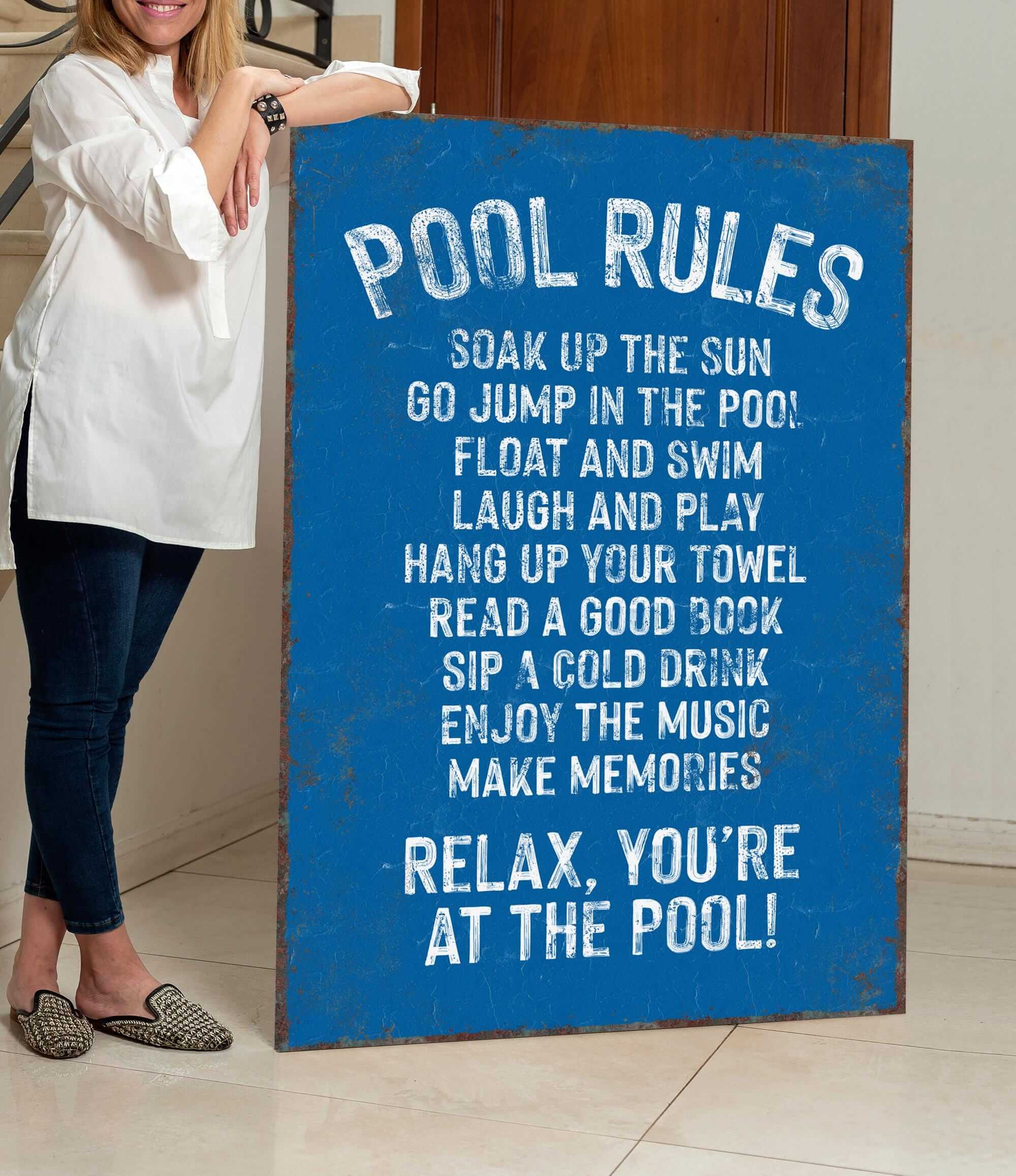 a woman standing next to a pool rules sign
