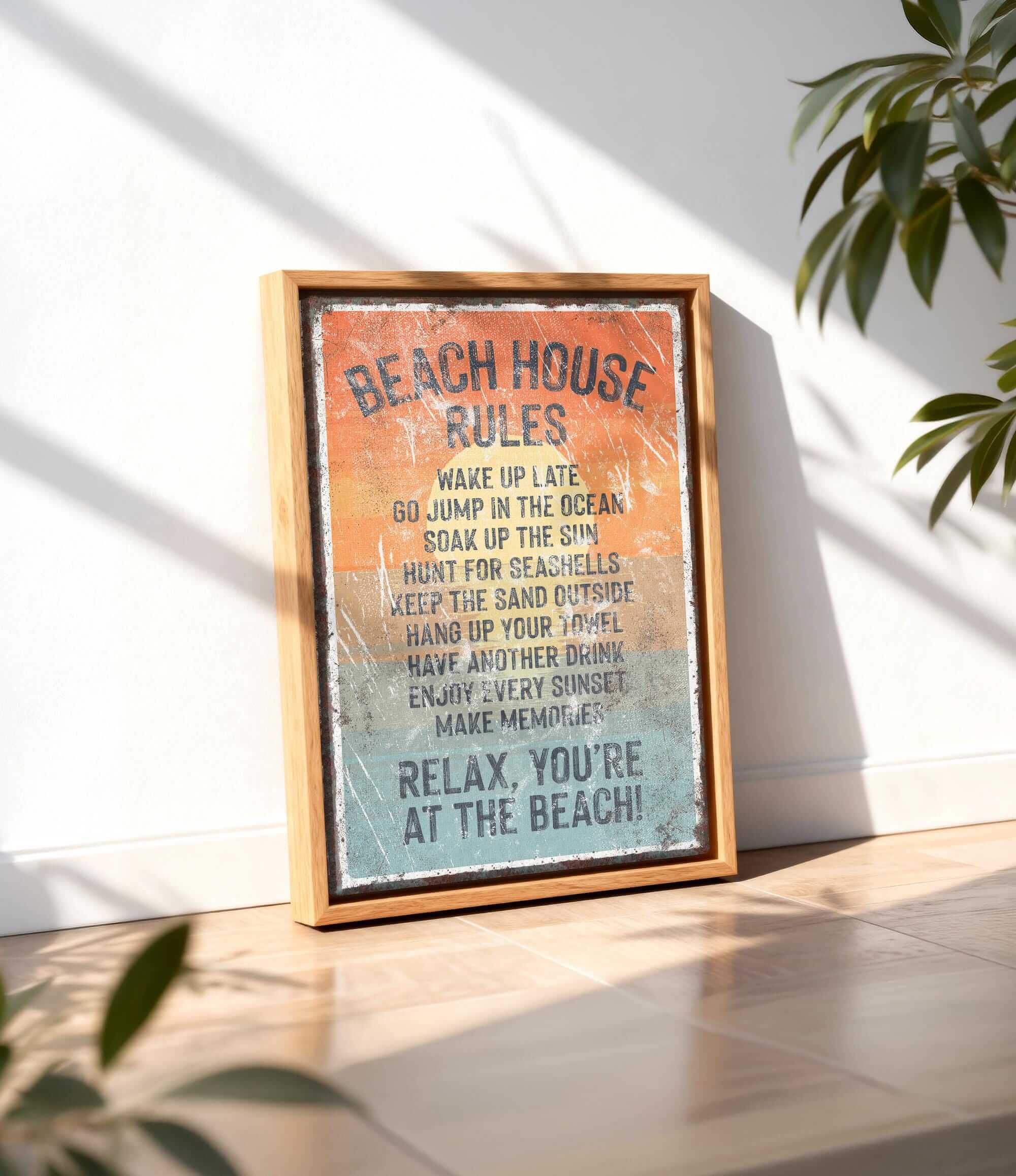 A framed sign with the text "BEACH HOUSE RULES" is displayed on a wooden floor, with a plant in the background.