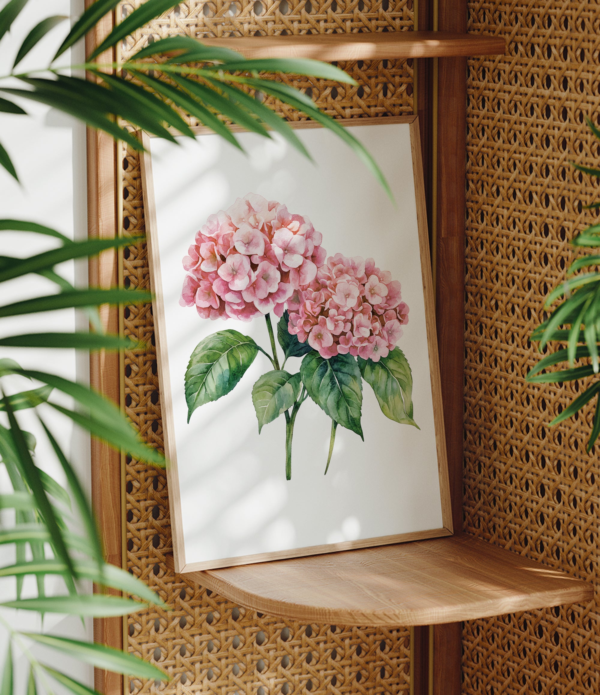 A framed watercolor painting of pink hydrangeas is displayed on a wooden shelf, surrounded by lush green plants.