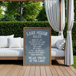 a sign on a wooden deck with a scenic view of a lake, surrounded by trees and greenery.