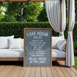 a sign on a wooden deck with a scenic view of a lake, surrounded by trees and greenery.