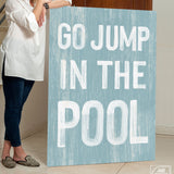 a woman holding a sign that says go jump in the pool