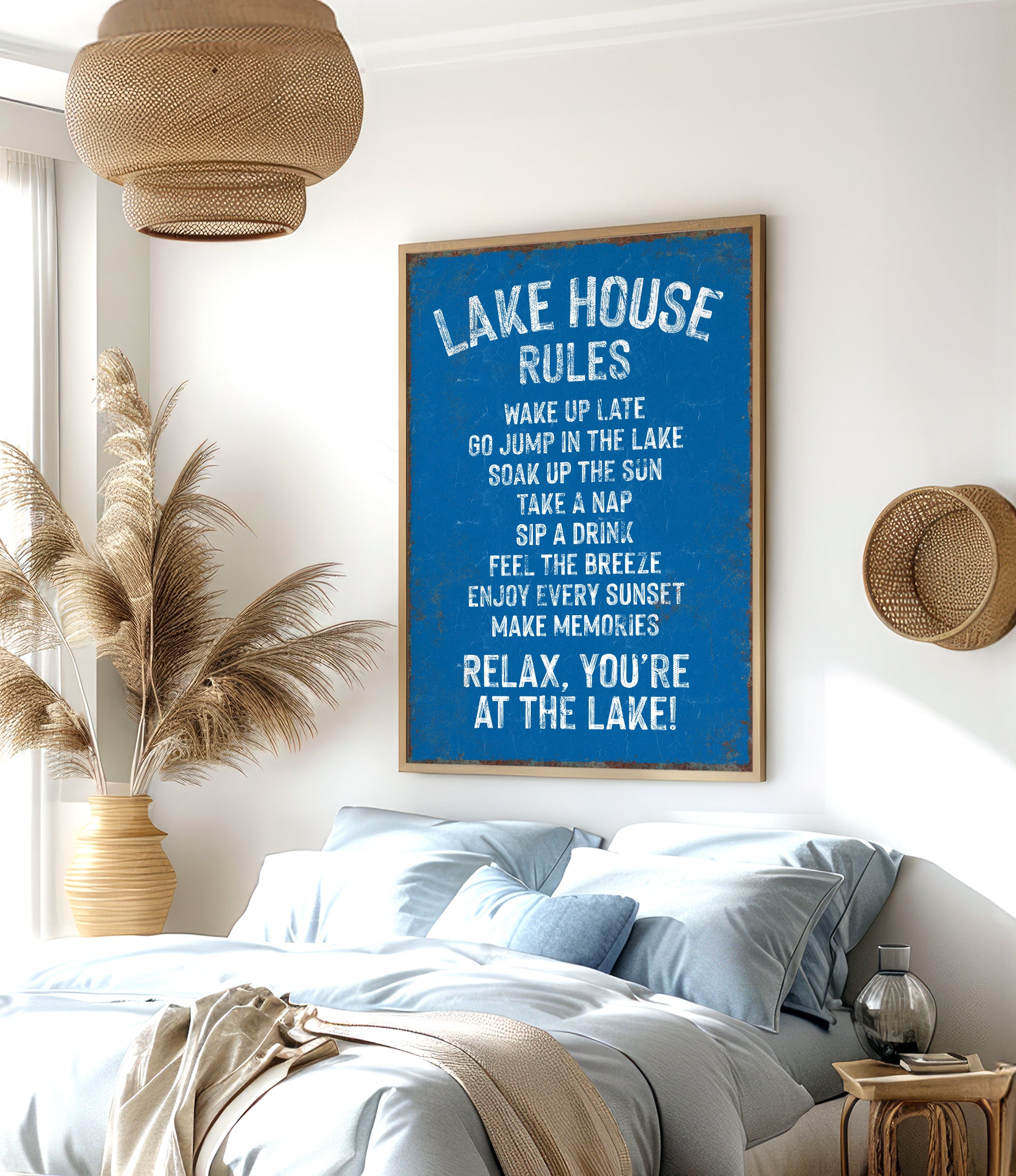 a bedroom with a large blue sign that reads "LAKESHORE RULES" hanging on the wall. The sign lists various lake-related activities and rules, such as "WAKE UP LATE GO JUMP ON THE LAKE COAT UP THE SUN TAKE A NAP FEEL THE BREEZE ENJOY EVERY SUNSET MAKE MEMORIES RELAX YOU'RE AT THE LAKE!" The room has a bed, a potted plant, and a woven basket, creating a cozy and relaxing atmosphere.