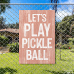 a sign on a fence that says let's play pickle ball