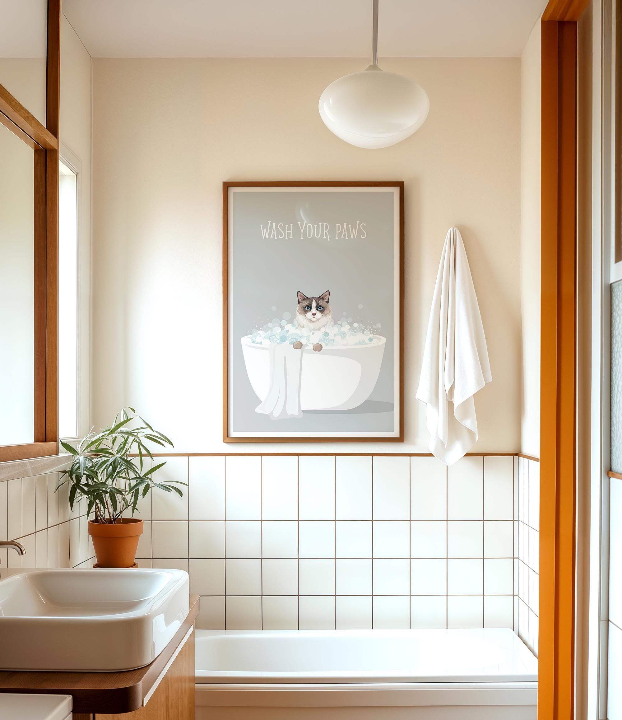 A bathroom with a framed poster of a cat in a bathtub, a towel rack, and a potted plant.