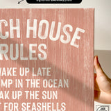 Hand holding a Beach House Rules Sign, Painted Wood, Coral—features white text and wood texture, making it perfect coastal wall art and unique beach house decor.