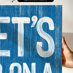 a hand holding a blue sign with white letters