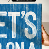 a hand holding a blue sign with white letters
