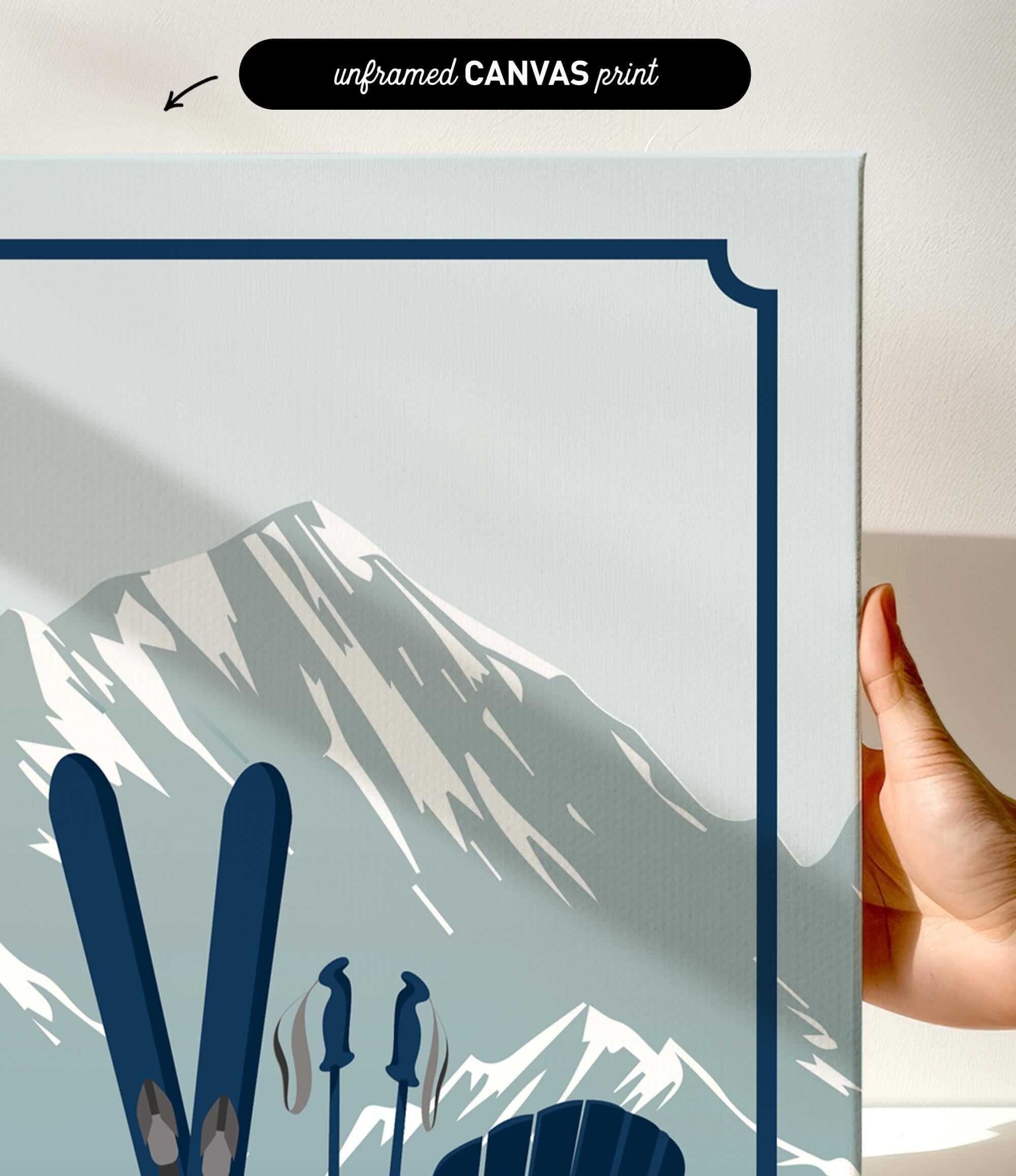 a hand holding a framed print of a mountain landscape with skis and ski poles.