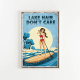 A framed poster with a woman paddleboarding on a lake, with the text "LAKESHAIR DON'T CARE" written above her.
