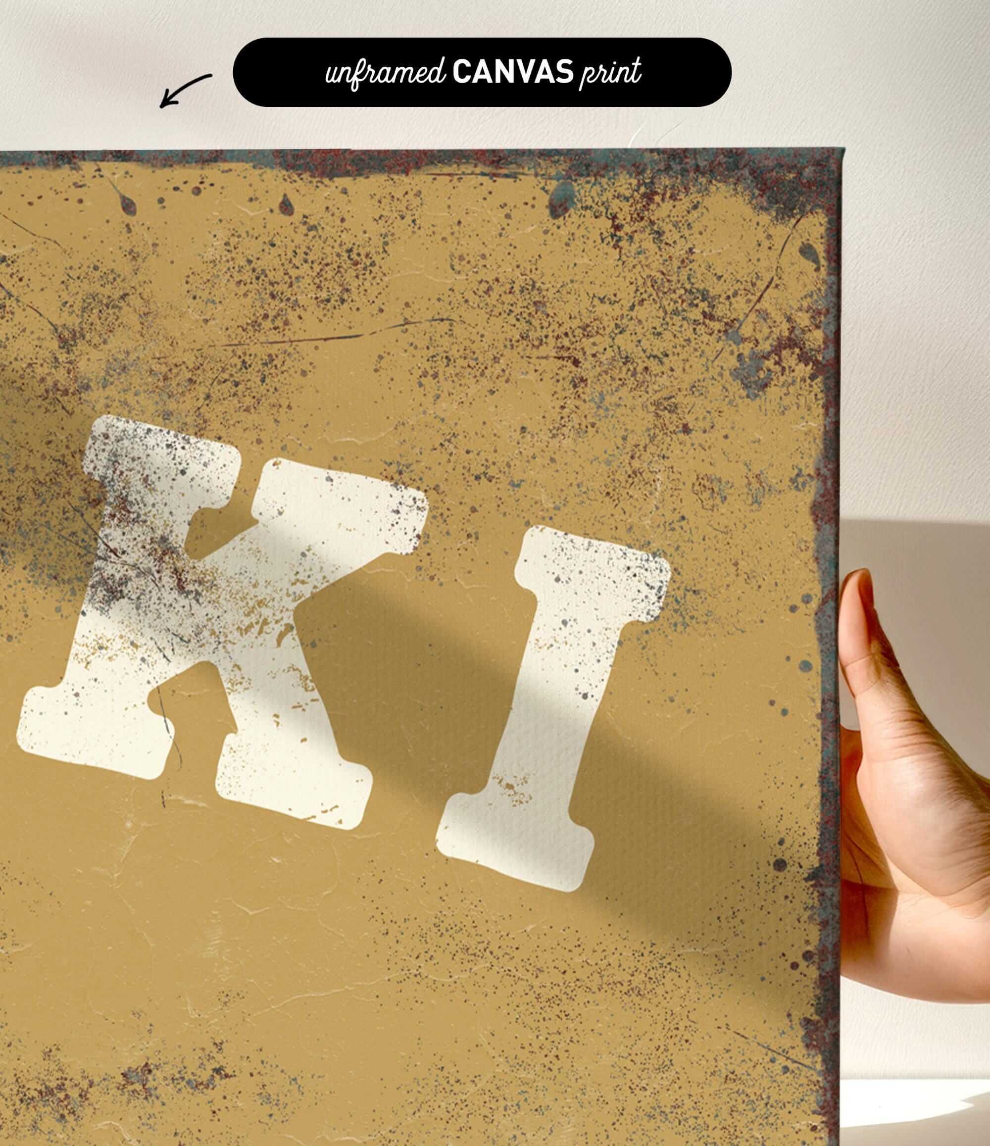 a hand holding a piece of artwork with a distressed, aged appearance. The artwork has a yellowish-brown background with splatters and a distressed texture, giving it a vintage or aged look.