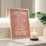 a framed sign on a bathroom counter with a lit candle in front of it, creating a relaxing atmosphere.