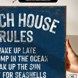 a hand holding a sign that says beach house rules