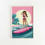 A woman in a pink and white swimsuit is paddleboarding on a pink surfboard, with a sunset and trees in the background.