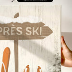 a hand holding up a sign with skis on it