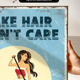 The image is a hand holding a framed print with a vintage-style illustration of a woman with long hair. The text on the print reads "Make hair care" and is in a bold, stylized font.