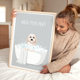 A woman is sitting on a bed holding a framed poster with a dog in a bathtub.