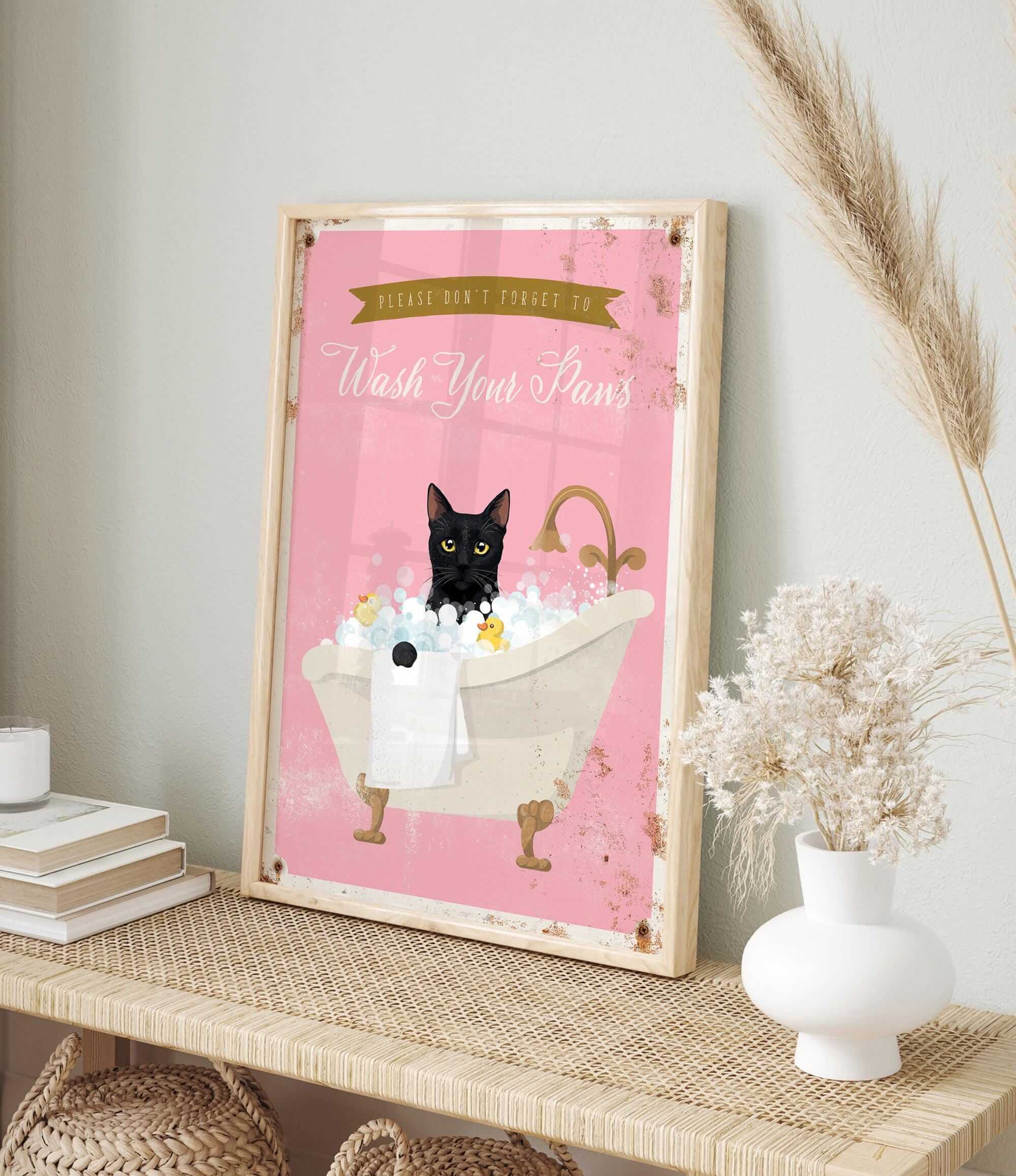 A framed poster with a black cat sitting in a bathtub filled with bubbles, accompanied by a pink background and a banner that reads "Please don't forget to wash your pans".