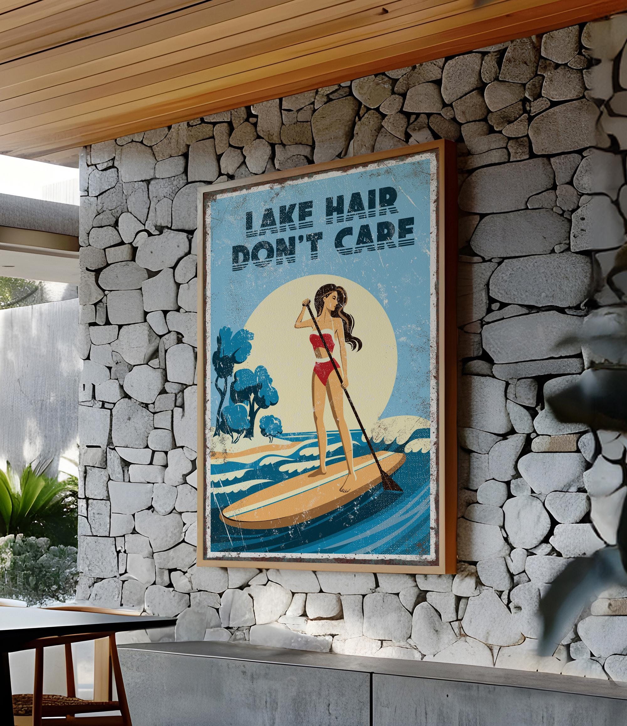a framed poster with a woman paddleboarding on a lake, with the text "LAKESHAIR DON'T CARE" displayed prominently.