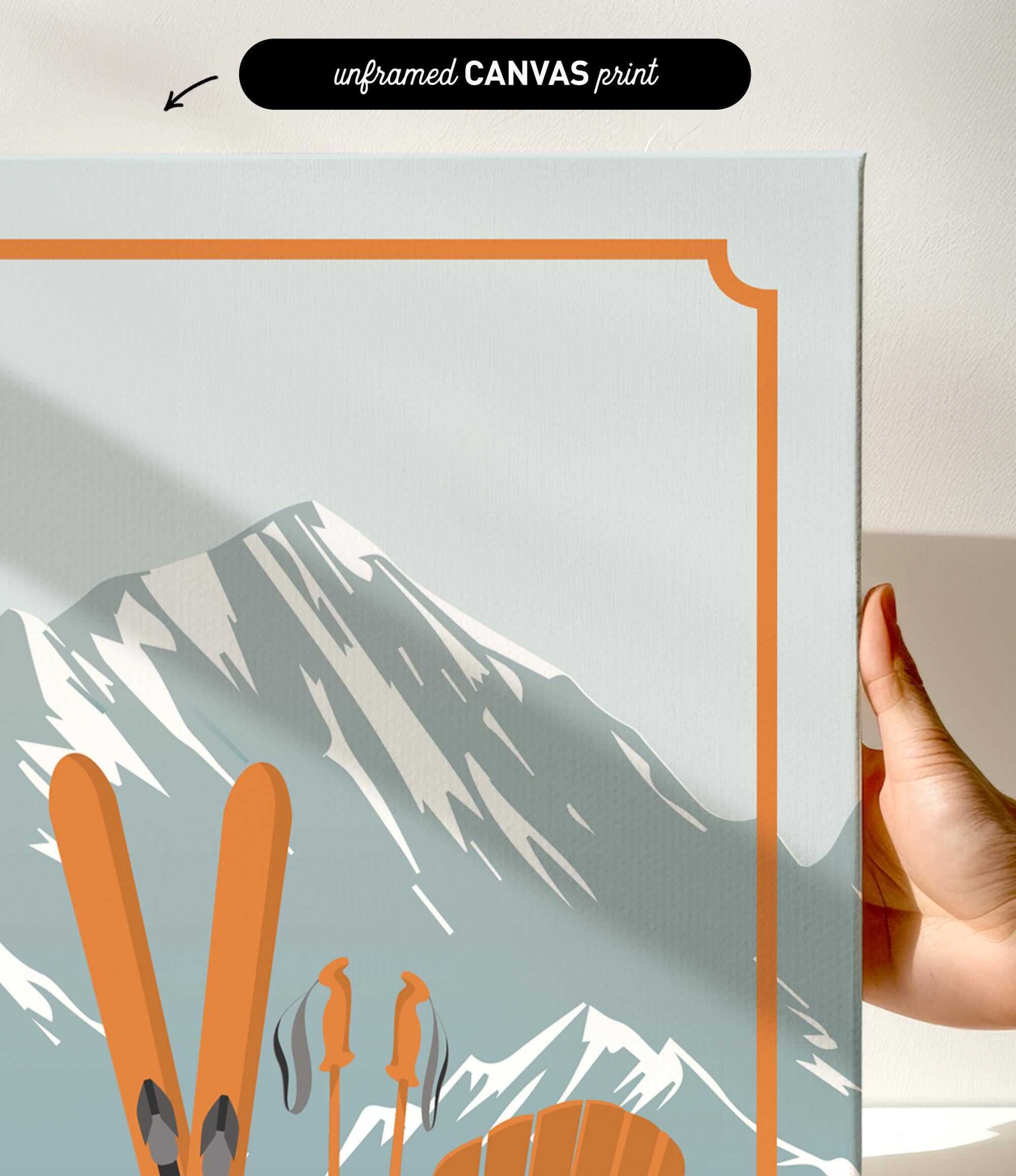 a hand holding a framed print of a mountain landscape with skis and ski poles.