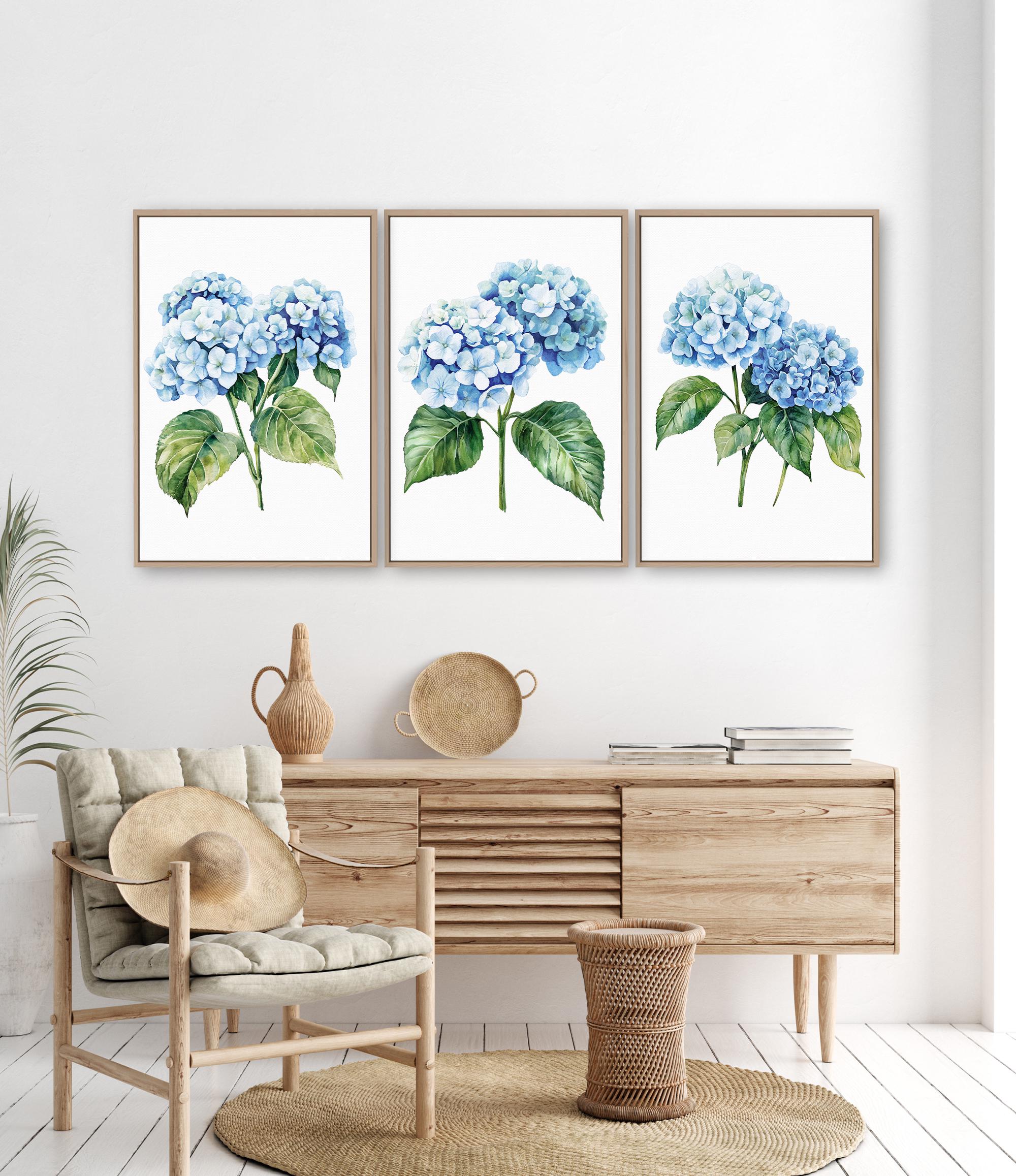 a living room with a wooden dresser, a woven basket, and a woven chair. Above the dresser, there are three framed watercolor paintings of blue hydrangeas hanging on the wall.