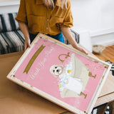 A woman is holding a framed poster with a dog in a bathtub, and the poster has a pink background with a white dog and the text "Please Wash Your Paws".