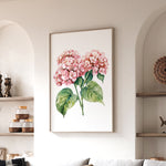 a framed painting of pink hydrangeas hanging on a wall in a living room.