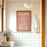 a bathroom with a framed sign that reads "LAKESHOUSE RULES" above a white sink. The sign provides a list of rules for guests to follow while staying at the lake house.