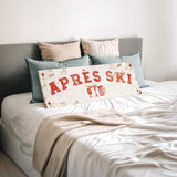 a bed with a white comforter and pillows, and a sign that says "APRÈS SKI" in red letters.