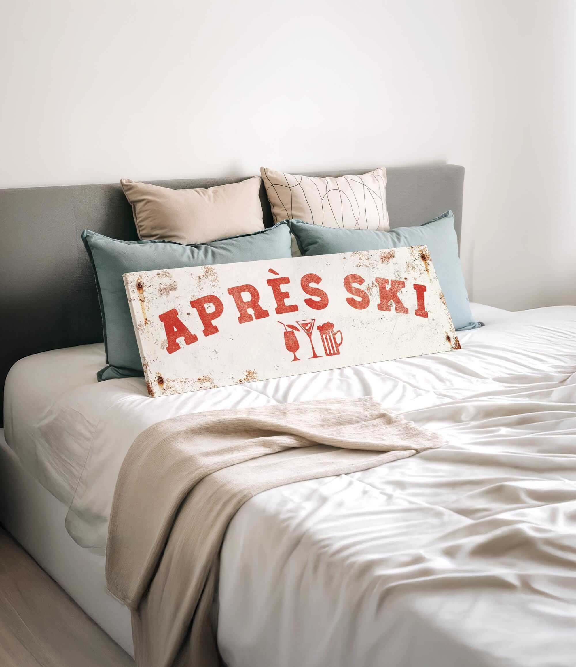a bed with a white comforter and pillows, and a sign that says "APRÈS SKI" in red letters.