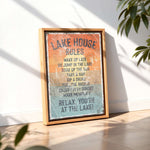 A framed sign with the text "LAKESHOUSE RULES" is displayed on a wooden floor, with a plant in the background.