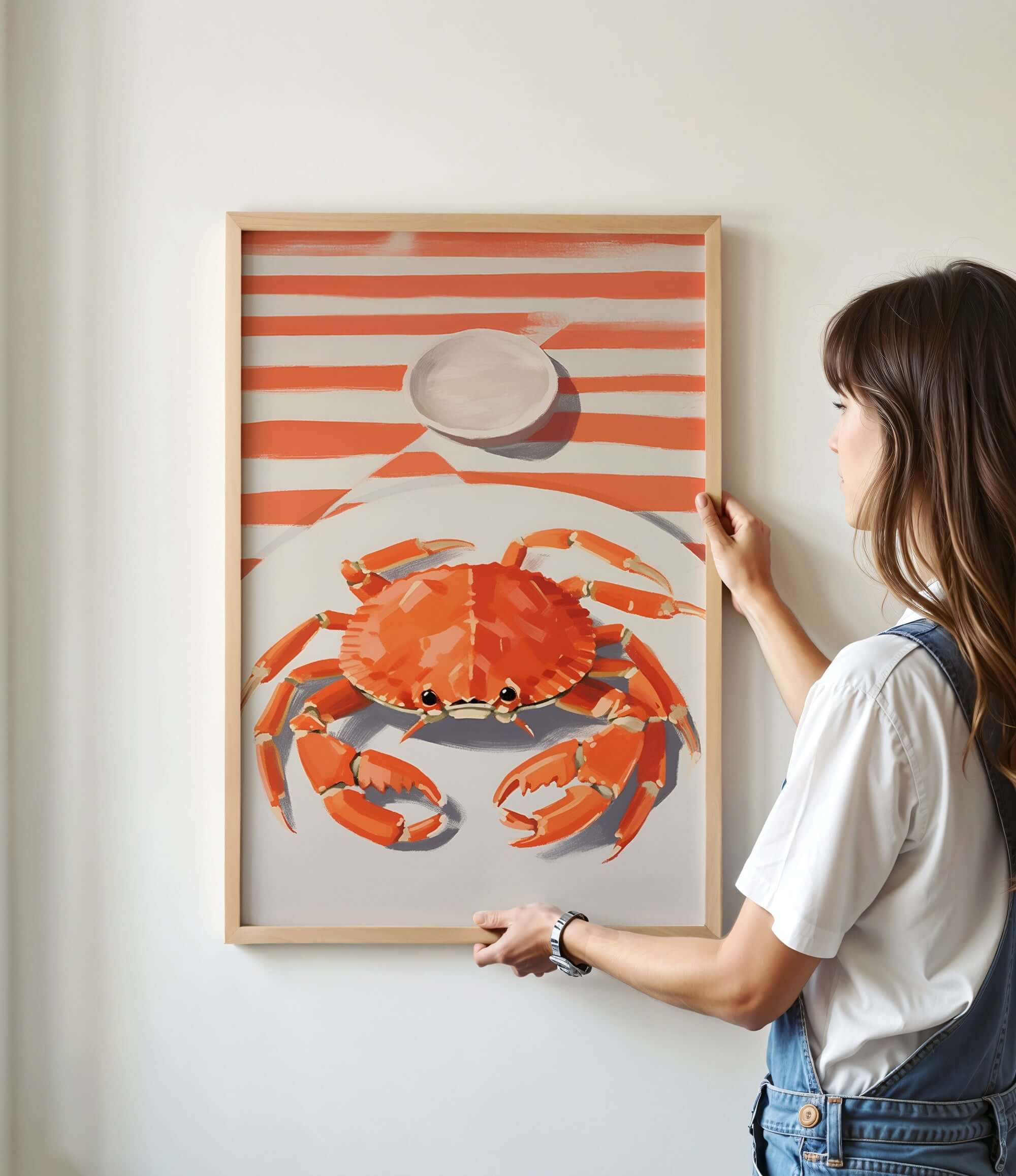 A woman is hanging a framed picture of a crab on a wall.