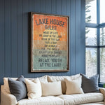 A framed sign on a wall that reads "LAKESHOUSE RULES" and lists various activities such as "WAKE UP LATE", "GO JUMP IN THE LAKE", "SOAK UP THE SUN", "TAKE A NAP", "DRINK", "FEEL THE BREEZE", "ENJOY EVERY SUNSET", and "MAKE MEMOJIES".