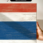 a hand holding a piece of wood with a flag painted on it