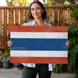 a woman holding a wooden sign with the flag of thailand