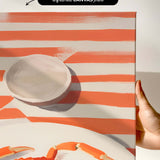 The image is a canvas print featuring a large crab and a white plate with a red rim, set against a striped background.