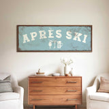 a wooden dresser with a framed sign above it that says "APRÈS SKI", and there are two white chairs and a vase with flowers on the dresser.