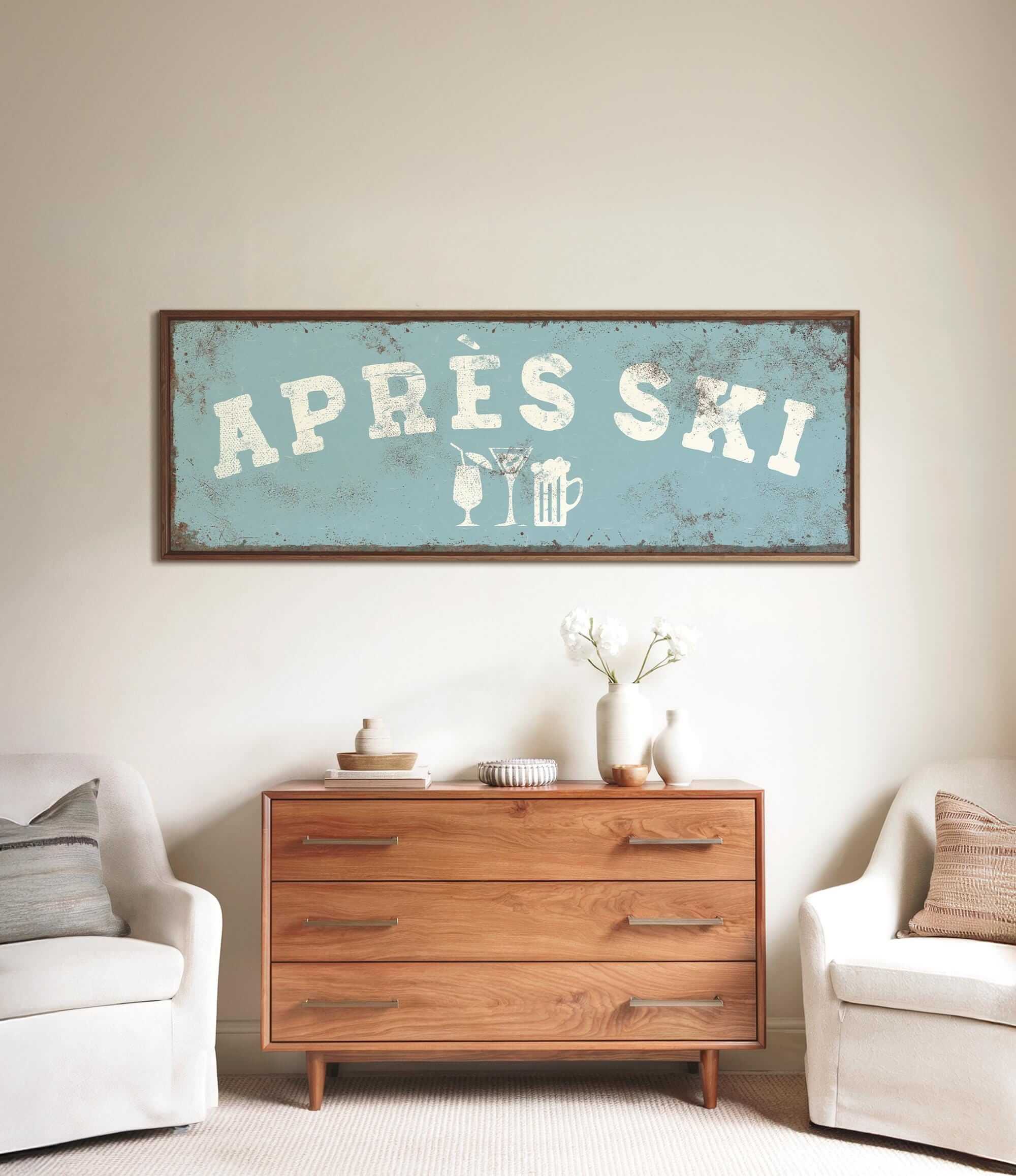 a wooden dresser with a framed sign above it that says "APRÈS SKI", and there are two white chairs and a vase with flowers on the dresser.