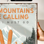 a person holding up a sign that says mountains are calling