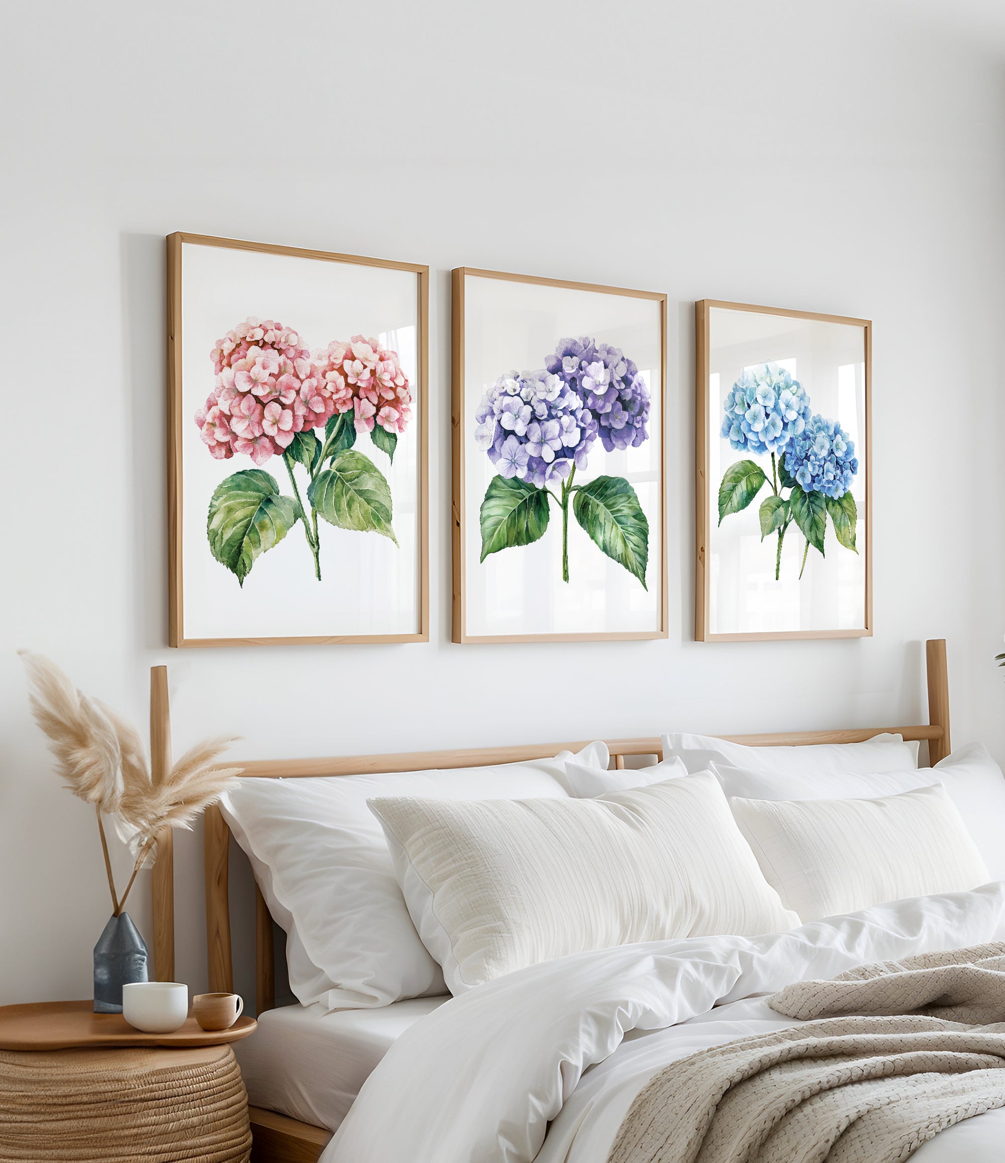 a bedroom with a bed and three framed watercolor paintings of hydrangea flowers hanging on the wall above it.