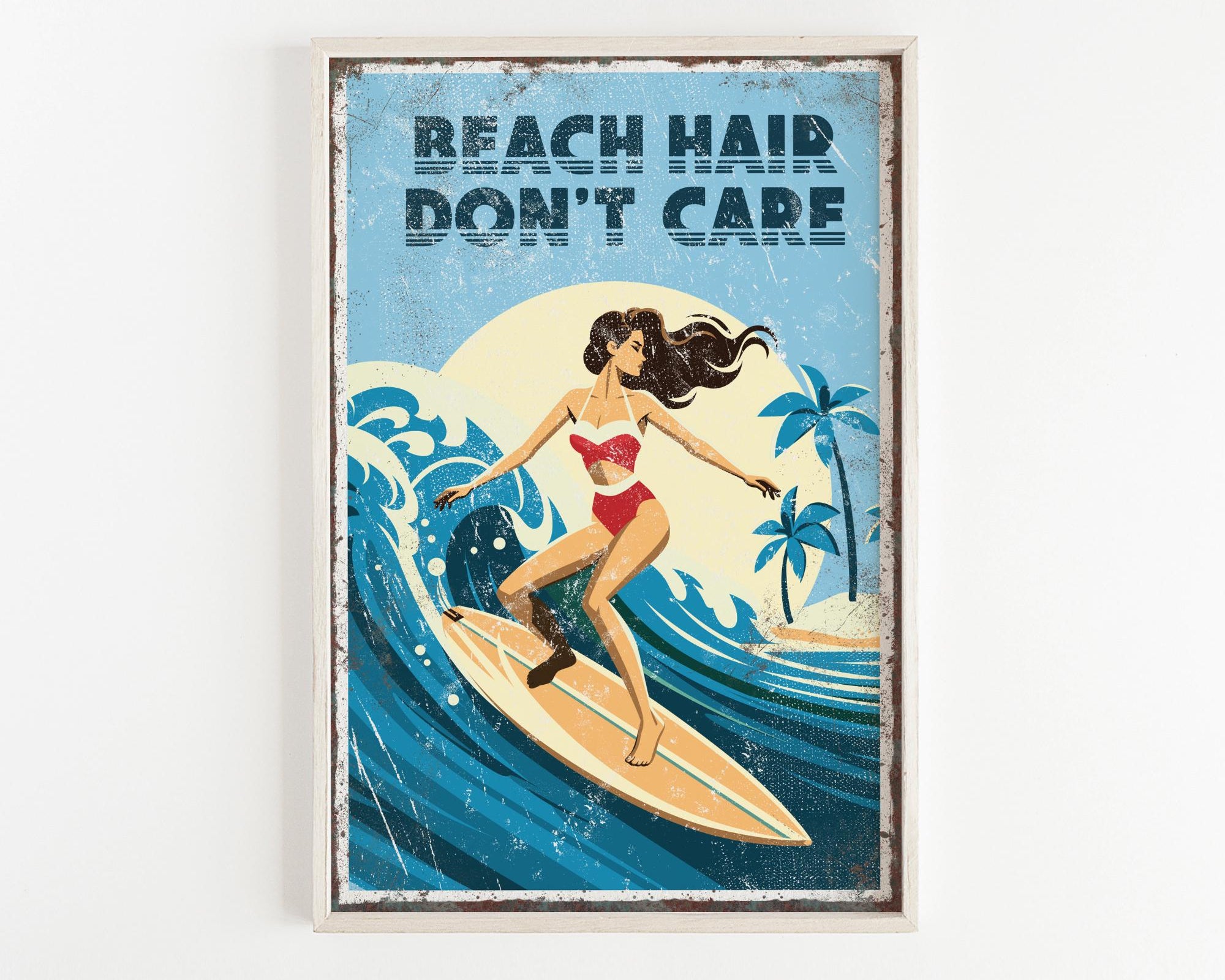 A framed poster with a woman surfing on a wave, with the text "REACH HAIR DON'T CARE" written above the image.