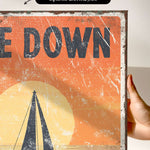 a hand holding up a poster with a sailboat on it
