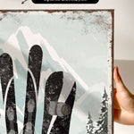 a hand holding up a picture of a pair of skis