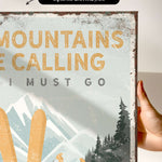 a hand holding a sign that says mountains are calling