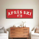 a living room with a large red sign that says "APRÈS SKI" above a wooden dresser. The dresser has a vase of flowers and a book on it. There are two white chairs in the room, and a small table with a lamp on it.