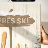 a hand holding up a sign with skis on it