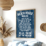 The Beach House Rules Sign, a blue painted wood nautical piece, hangs on the wall listing relaxing activities, adding cozy beach house decor to any room.