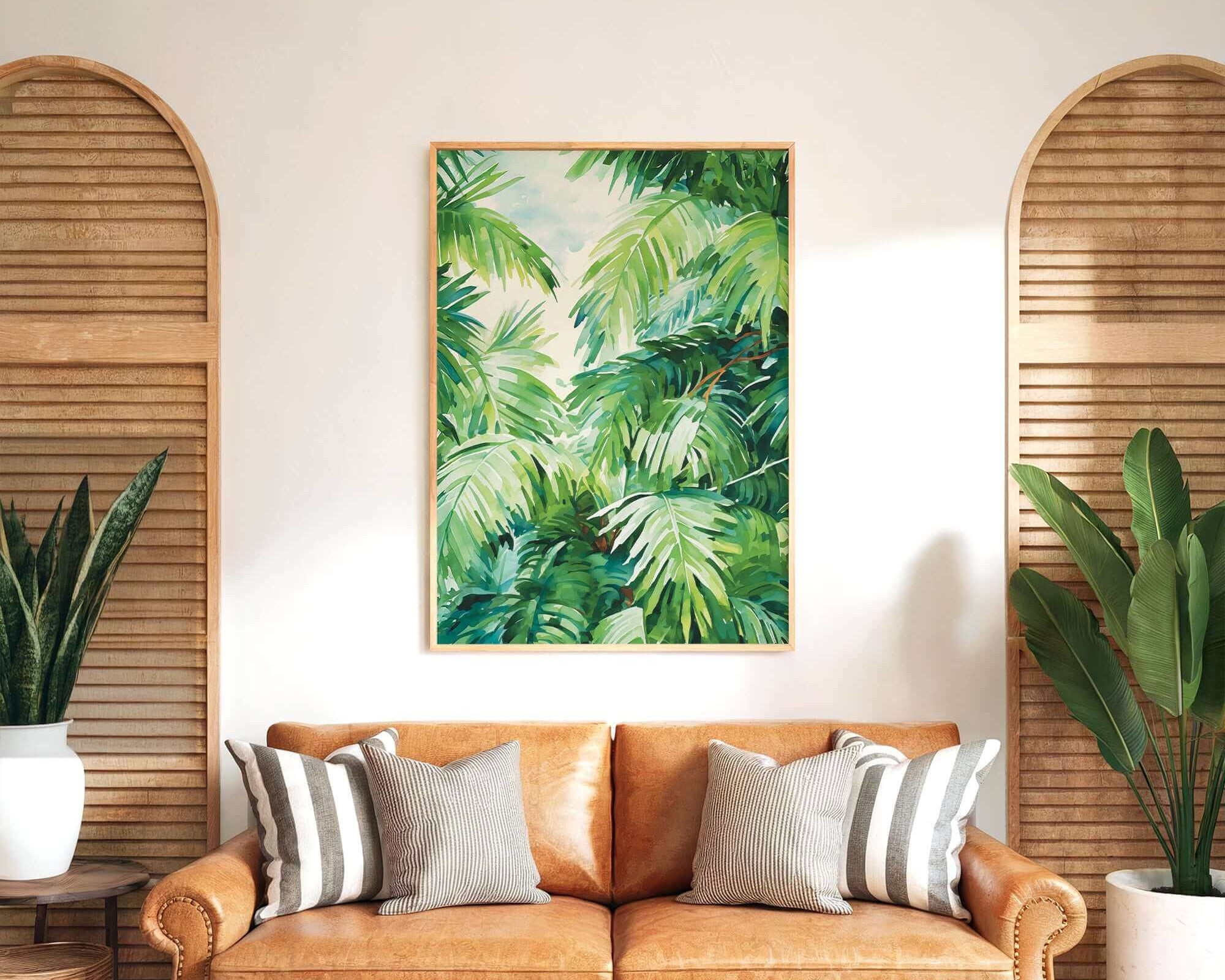 a living room with a large, vibrant painting of lush green palm leaves hanging on the wall above a brown leather sofa with striped pillows.