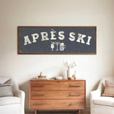 a wooden dresser with a framed sign above it that says "APRÈS SKI", and there are two white chairs and a vase with flowers placed in front of the dresser.